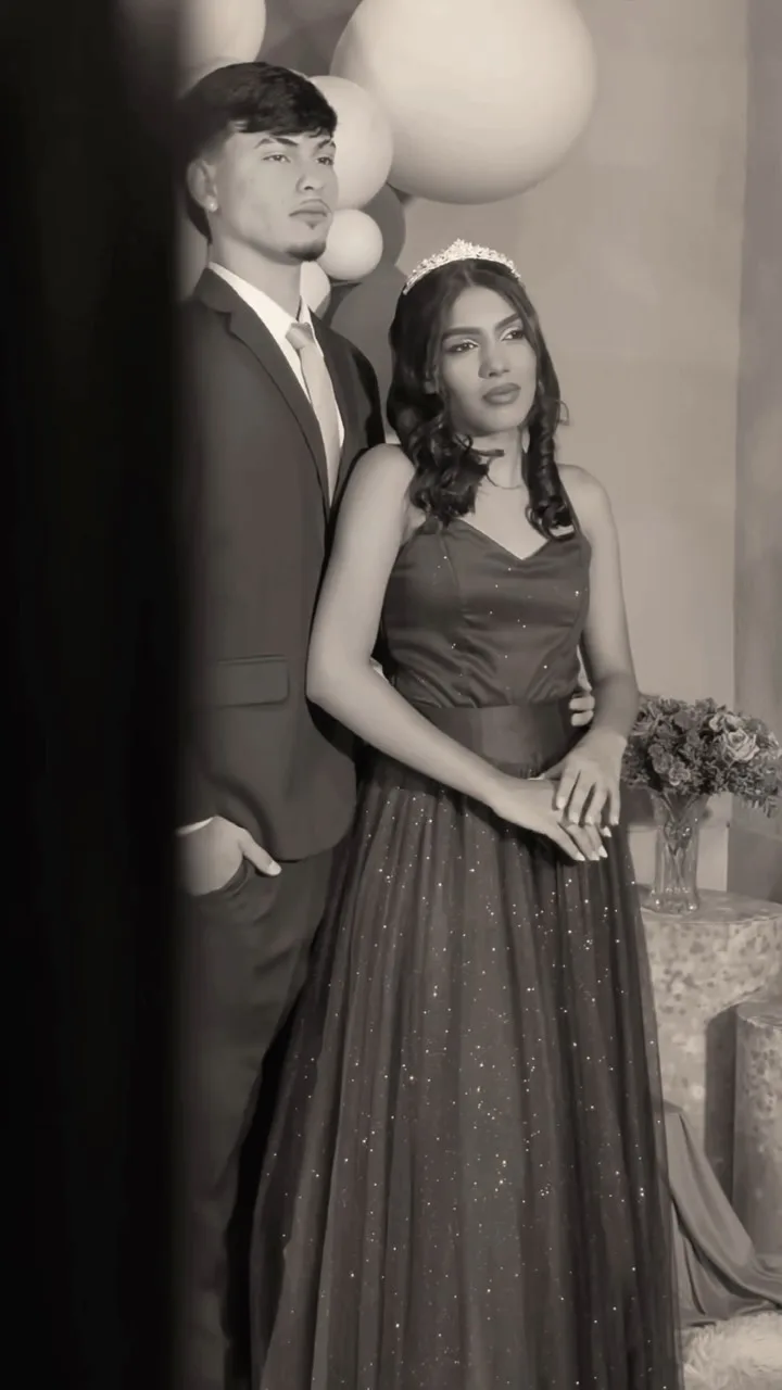 Casal com roupas de festa posa de mãos dadas em fotografia em preto e branco.